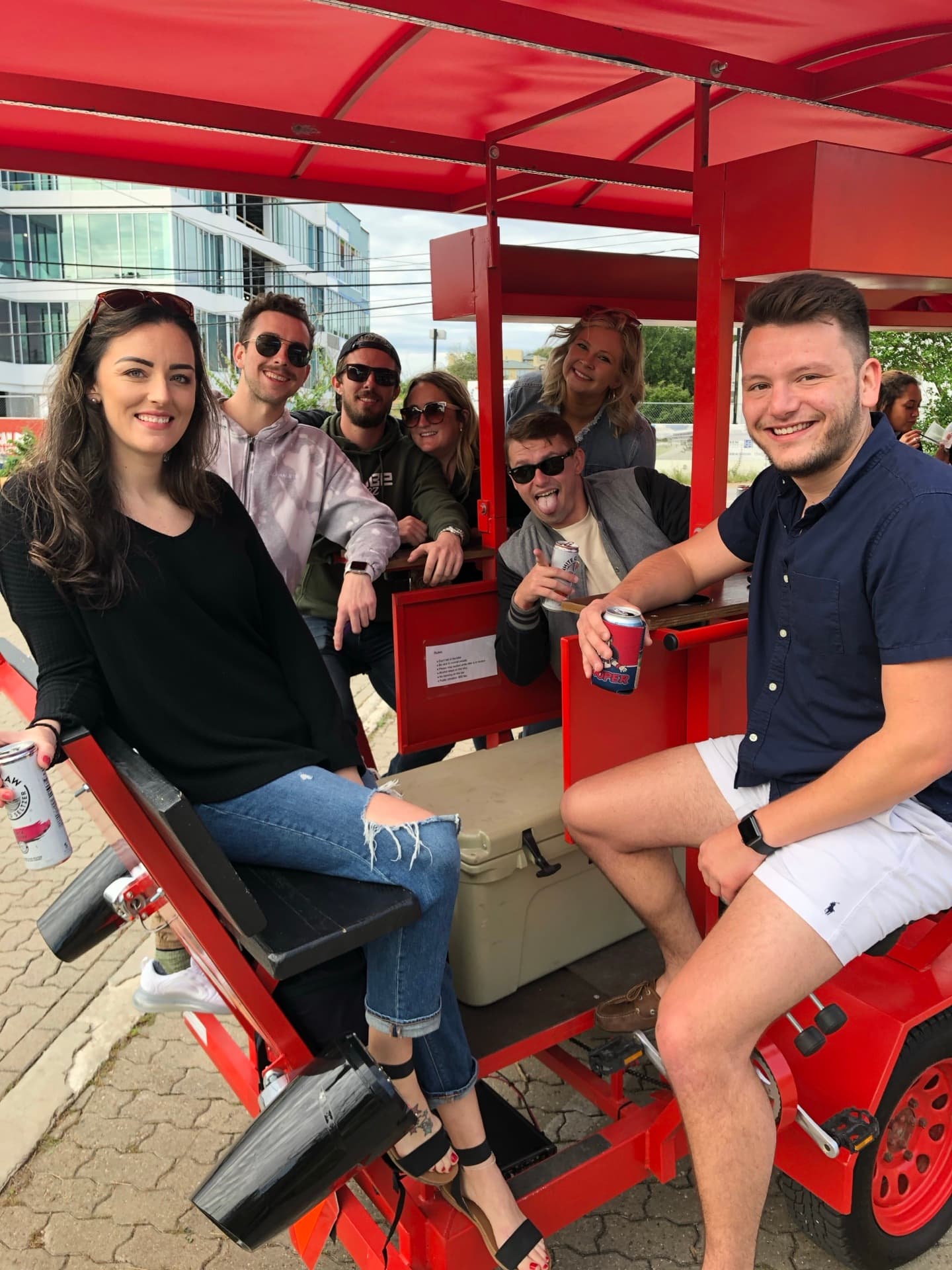10 friends pedaling on red BYOB party bike through downtown Austin