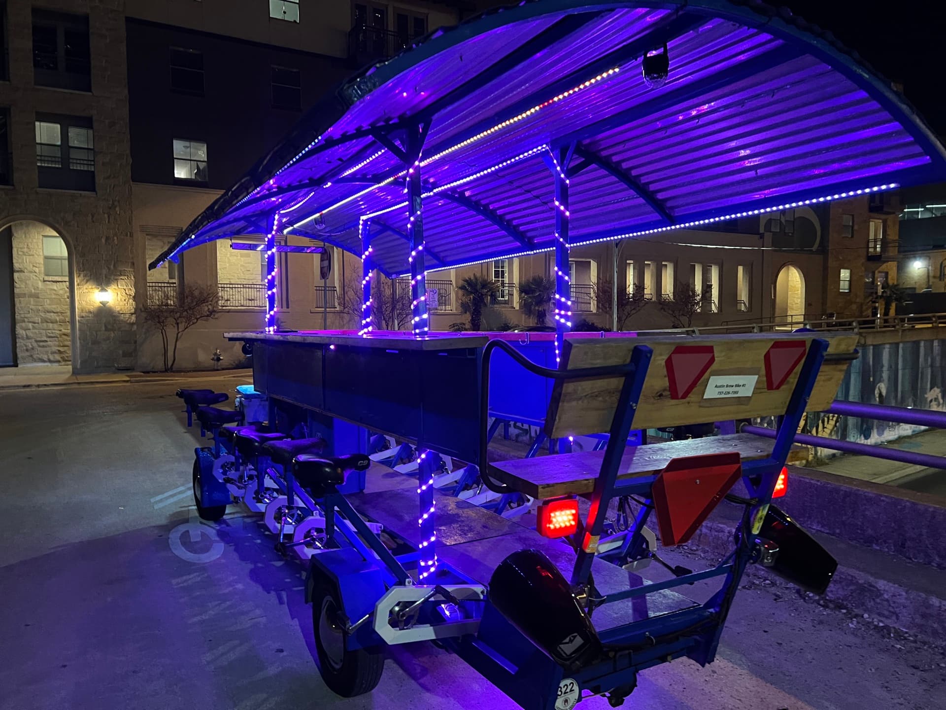 BYOB party bike lit up with purple LED lights cruising downtown Austin at night